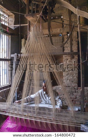 VARANASI, INDIA - CIRCA FEBRUARY 2011: Man weaving with an ancient Jacquard weaving machine, also called hand loom.