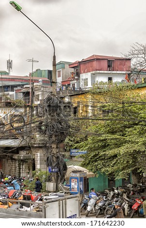 HANOI, VIETNAM - CIRCA MARCH 2012: Street scene showing off nested electrical wiring. Unbelievable mess of wires above parking lot of motorcycles.
