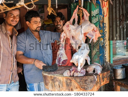 VELLORE, INDIA - CIRCA OCTOBER 2013: Butchers cutting mutton on a wooden block in front of their shop.