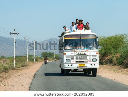 RAJASTHAN, INDIA - CIRCA FEBRUARY 2011: Public transport bus with plenty of passengers on the roof driving on the road.