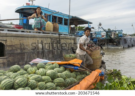 CAN THO, VIETNAM - CIRCA APRIL 2012: Retailer with water melons meets wholesaler at Cai Rang floating market. Small retailer sloops moves along larger wholesaler barge.