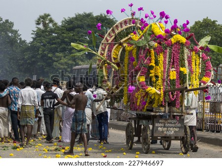 GINGEE, INDIA - CIRCA OCTOBER 2013: A funeral procession with only male participants proceeds through the streets of Gingee. The deceased man is exposed on a pushcart covered with flowers.