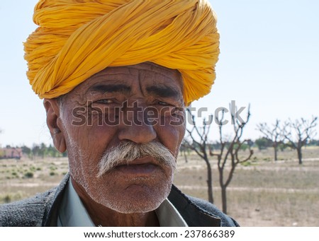 RAJASTHAN, INDIA- FEBRUARY 9, 2011: Closeup of an older, dark-skinned, bearded Rajasthan\'s man face with orange turban.