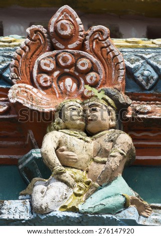 KUMBAKONAM, INDIA - OCTOBER 12, 2013: Mahalingeswarar Temple. Wear and tear have damaged the lesser Gopurams. Cute statue of kissing couple. A twig of a fresh grown tree peeps between their faces.