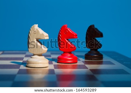 Three chess pieces on a chessboard horse and blue background