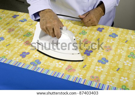 A woman irons colorful fabric to be used in making a pillow case.