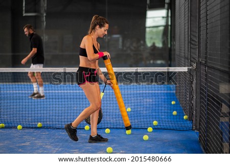 Girl collects padle or tennis balls in the middle of the court Stock fotó © 