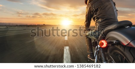 Foto Bild Motorradfahren bei Sonnenuntergang auf der leeren Straße bei einer Motorradtour. copyspace für Ihren individuellen Text.