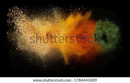 Freeze motion of various spice explosion, abstract culinary background. Isolated on black background