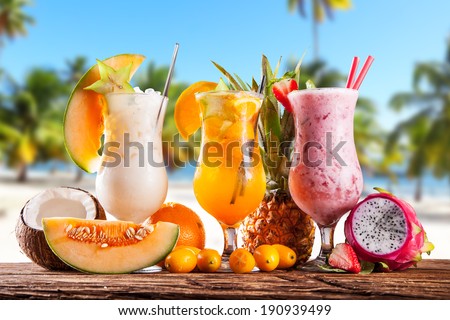 Exotic summer drinks served on wood. Blur sandy beach as background
