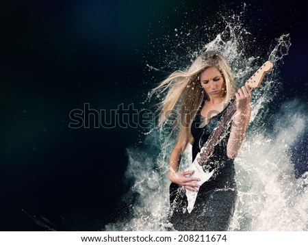 Beautiful young woman playing on electric guitar in water splashes, isolated on black background