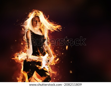 Portrait of burning young attractive blond woman playing on electric fire guitar