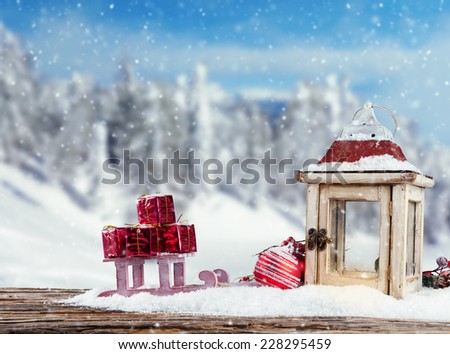 Christmas still life with lantern, gift and sledge. Blur landscape on background