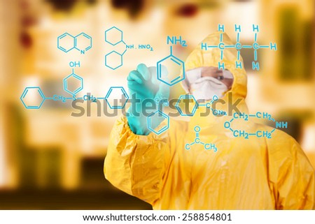 Laboratory man in chemical protective dress drawing chemical formula on foreground