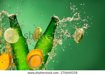Bottles of fruit beer with splash around on green background.