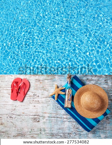 Swimming accessories on wooden mole placed next to water surface of pool. Shot from bird-eye perspective