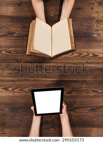 Woman hands holding blank old book and modern tablet device on wooden planks. Classical and modern reading concept