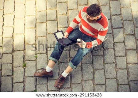 Trendy hipster young man with digital book and smart phone. Shot from aerial view