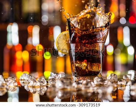 Glass of cola splashing out, placed on bar counter