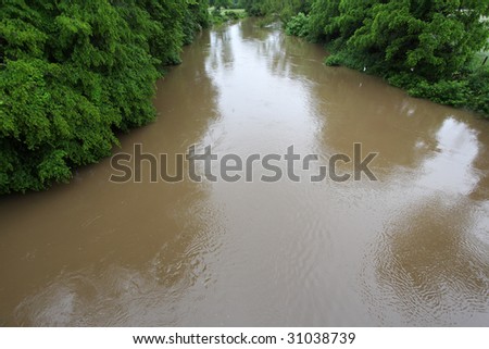 Brown swollen river overflows its banks