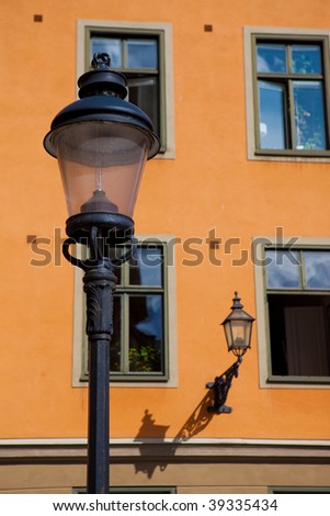 Street lamp and wall lantern of bright orange building with windows in Gamla Stan, Stockholm, Sweden