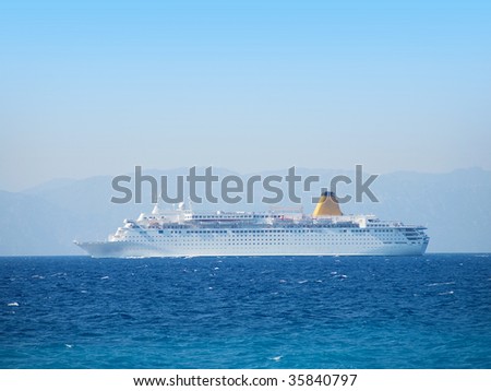 Big cruise vessel side view with water surface in front and mainland in back.