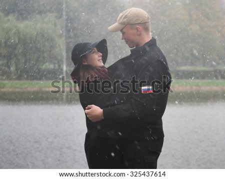Autumn, the first snow. Strong wind. Man and woman together in the snow. A man hugs girl. Cold, windy. Love, feelings, emotions. Very emotional picture.