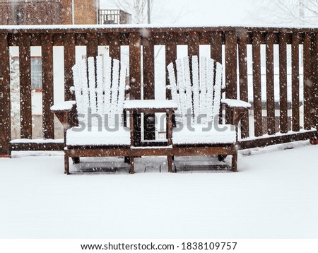Two wooden garden chairs sit on a terrace covered with snow in winter during snowfall Stock foto © 