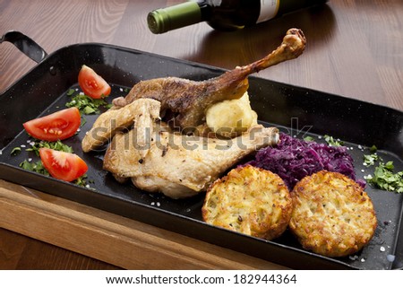 Baked duck and chicken legs with red cabbage, potato dumplings and potato pancakes