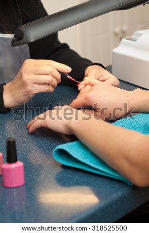 Professional manicurist painting the nails of her client with clear polish