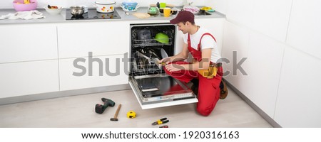 Repair of dishwashers. The master has come home and is repairing the dishwasher