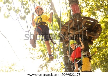 Happy child climbing in the trees. Rope park. Climber child. Early childhood development. Roping park. Balance beam and rope bridges. Rope park - climbing center