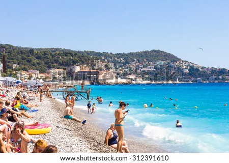 NICE, FRANCE - AUGUST 23: Tourists enjoy the good weather at the beach on August 23, 2015 in Nice, France. The beach and the waterfront avenue, Promenade des Anglais, are full almost all the year.