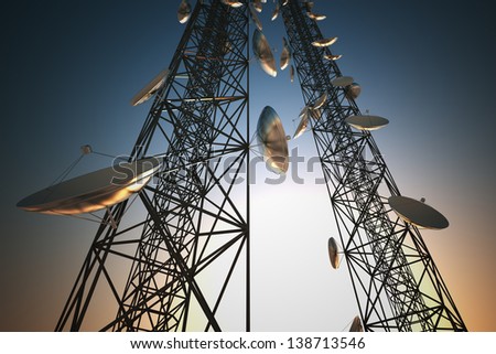 Two tall telecommunication towers with antennas in twilight sky.