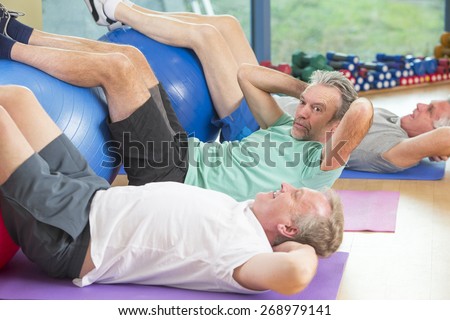 Three seniors using gym equipment for sit-ups at the gym