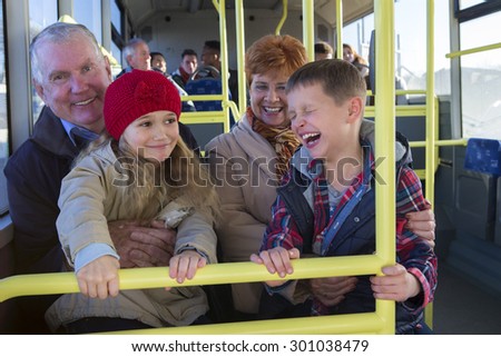 Grandparents taking their grandchildren out via the bus. The children are sitting on their grandparents knees.