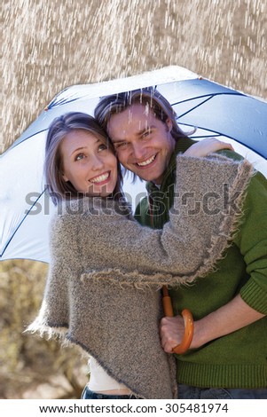 Young couple smiling under an umbrella in the rain