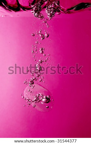 Ice splashing underwater against pink background