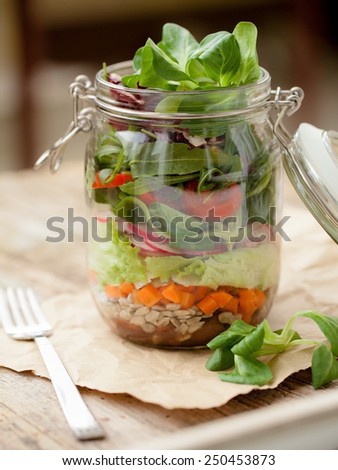 Lettuce, tomato and other vegetables in glass jar