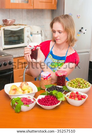 The image of the woman preparing jam from berries on kitchen
