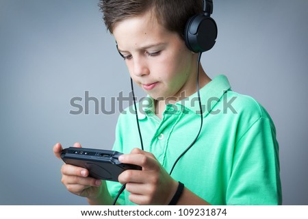 Boy playing game console against grey background
