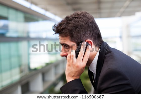 Close-up of a successful young business man talking on cell phone at modern office