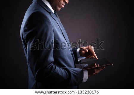 Businessman working on a digital tablet against black background