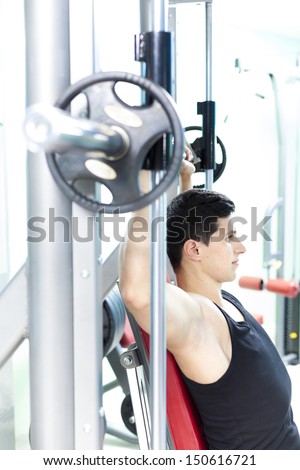 Handsome young man lifting heavy weights at the gym