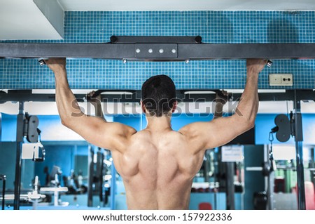 Rear view of young bodybuilder training his back