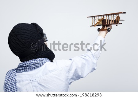 Rear view of a kid playing with toy airplane against gray background