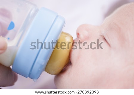 Close-up of mother hands feeding his baby with a milk bottle