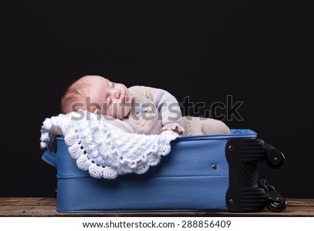 Newborn baby sleeping inside trolley bag