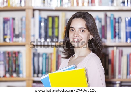 Female student holding books at the university library