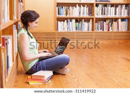 Smiling female student using the laptop at the library